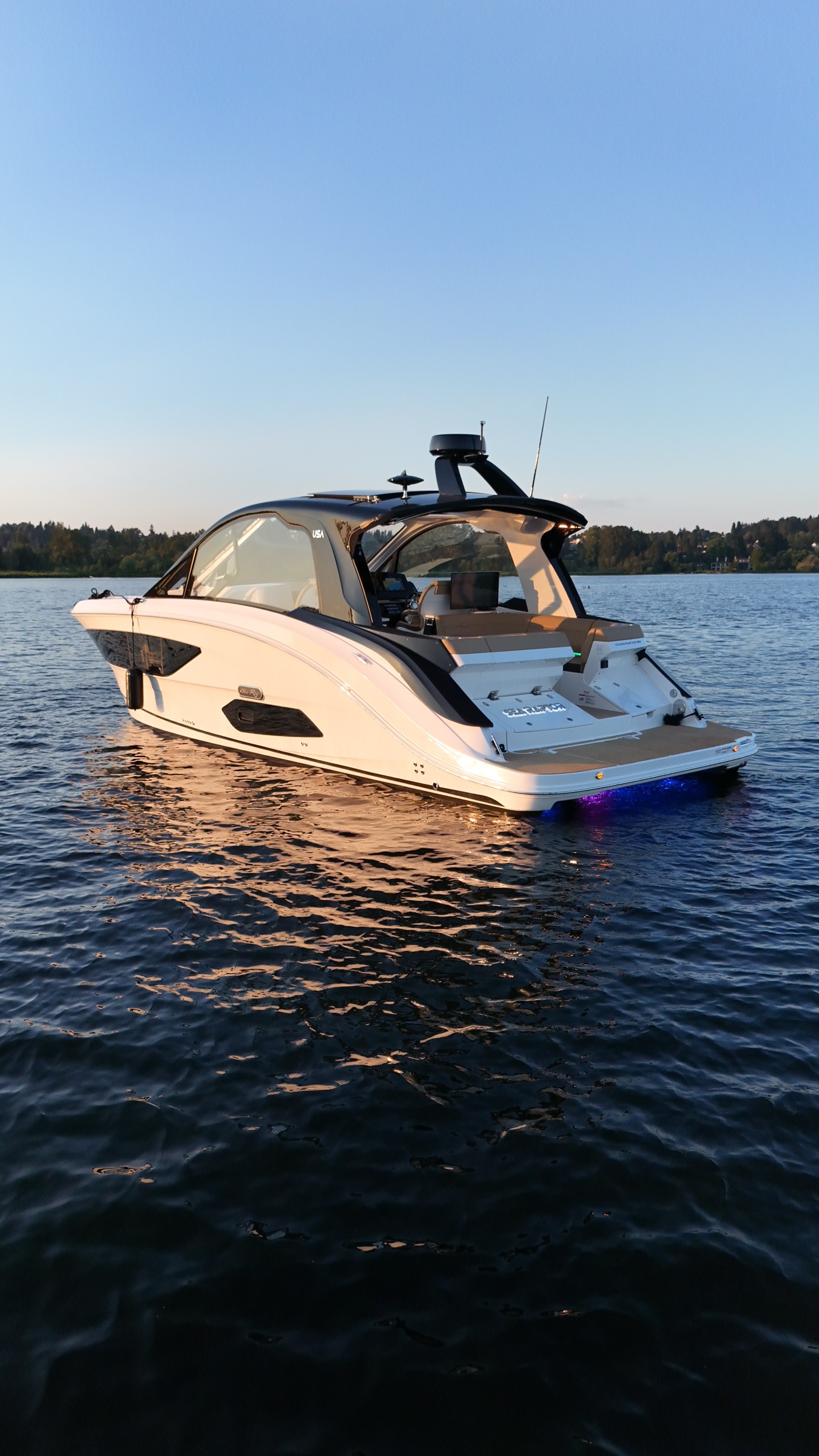 Side profile of Sea Raptor at dusk with blue underwater lights on glassy water